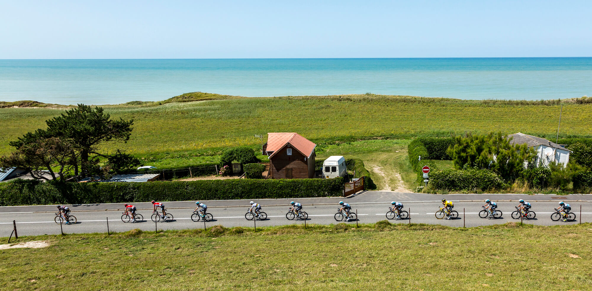 Line of cyclists racing on road by seaside