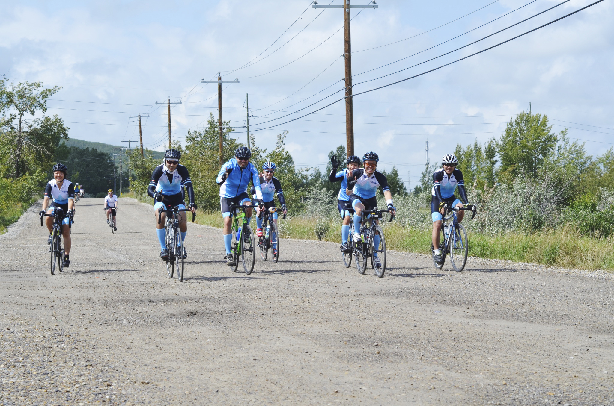 Nine Reinvent employees cycling while wearing blue and white team uniforms